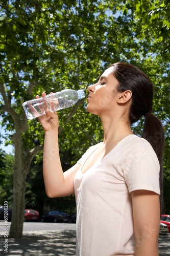 pretty brunette woman drinking water from plastic bottle.