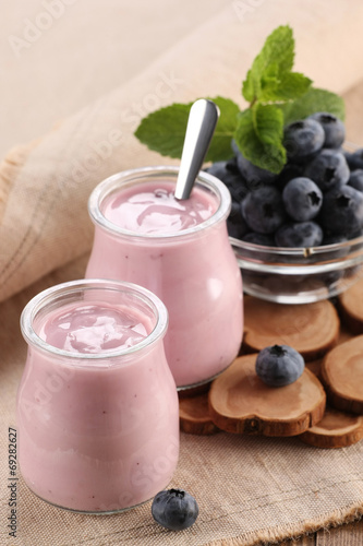 yogurt with blueberries in a glass jar and blueberries in a glas