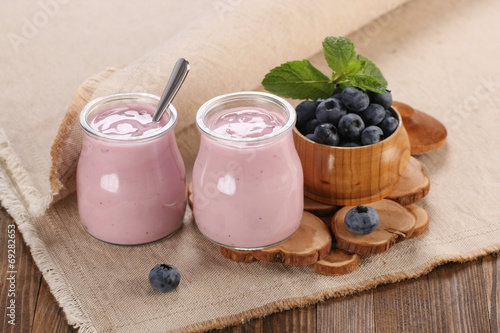 yogurt with blueberries in a glass jar and blueberries in a wood