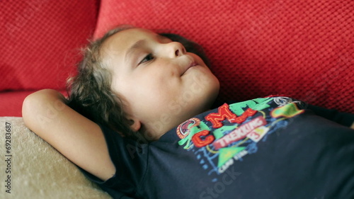 Boy lying on red couch and singing a song photo