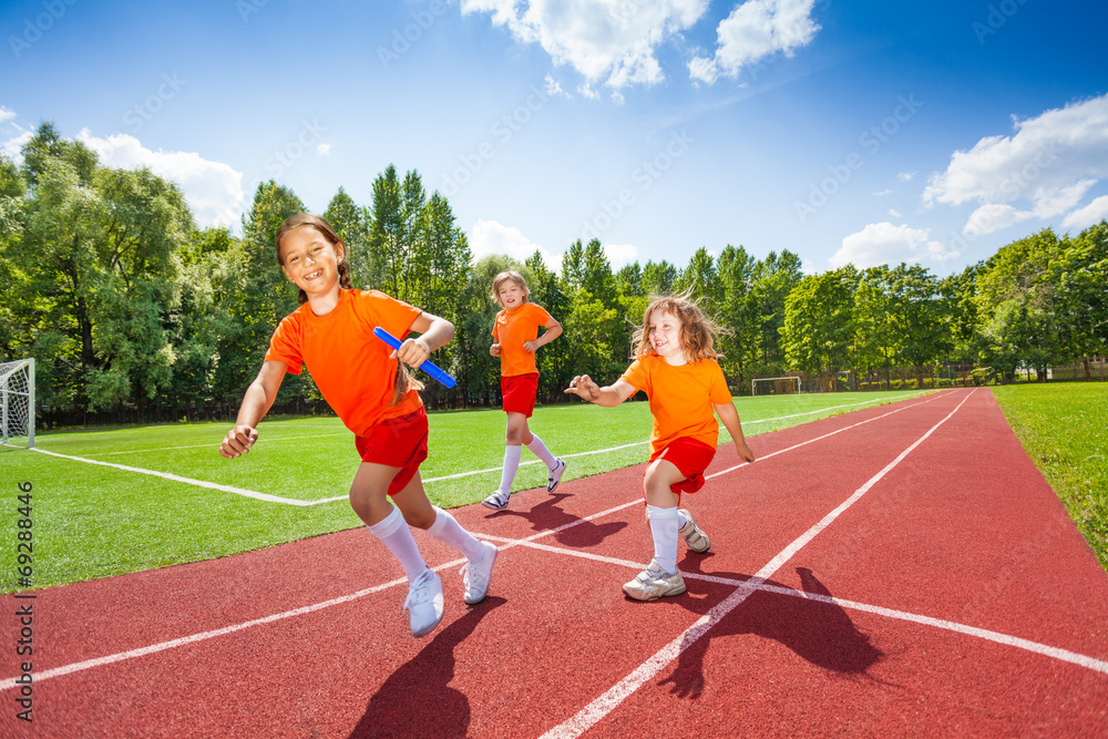 Obraz premium Three girls with one relay baton running