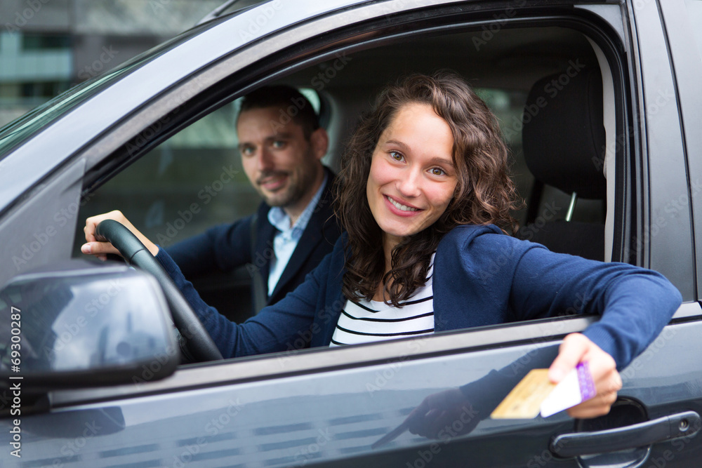 Couple in his car paying at a toll booth Couple in his car paying at a toll booth
