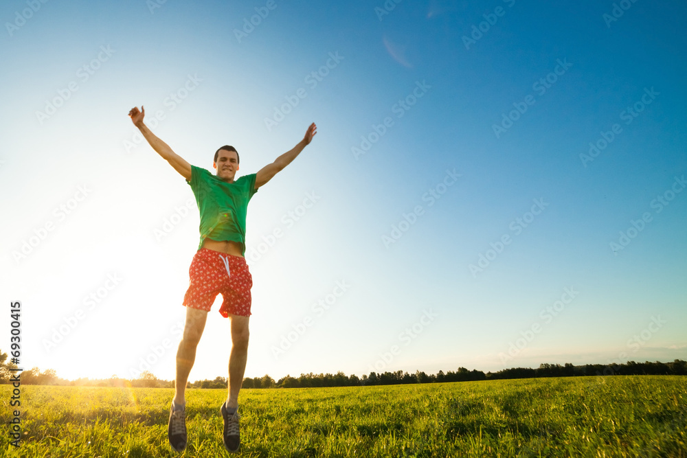 Young man jumping on meadow with dandelions Young man jumping on meadow with dandelions