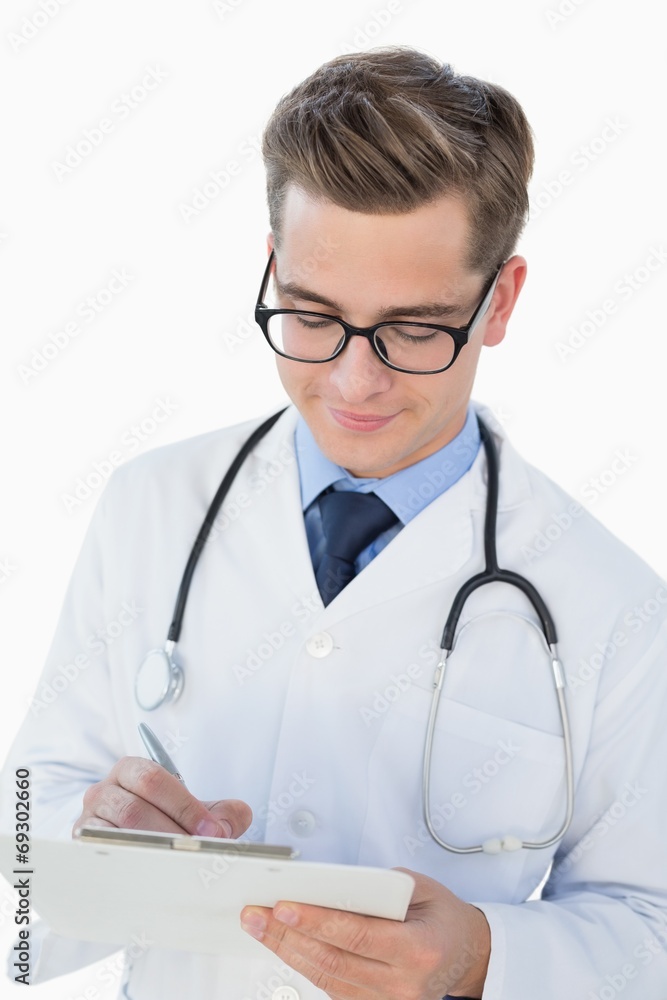 Smiling young doctor writing on clipboard