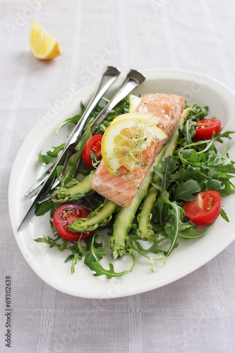 Portion steam salmon with a salad of arugula and fresh asparagus