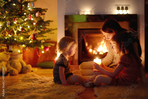 Obraz na plátne Happy family by a fireplace on Christmas