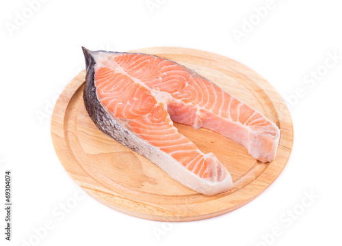 Fresh salmon steak on wooden platter.