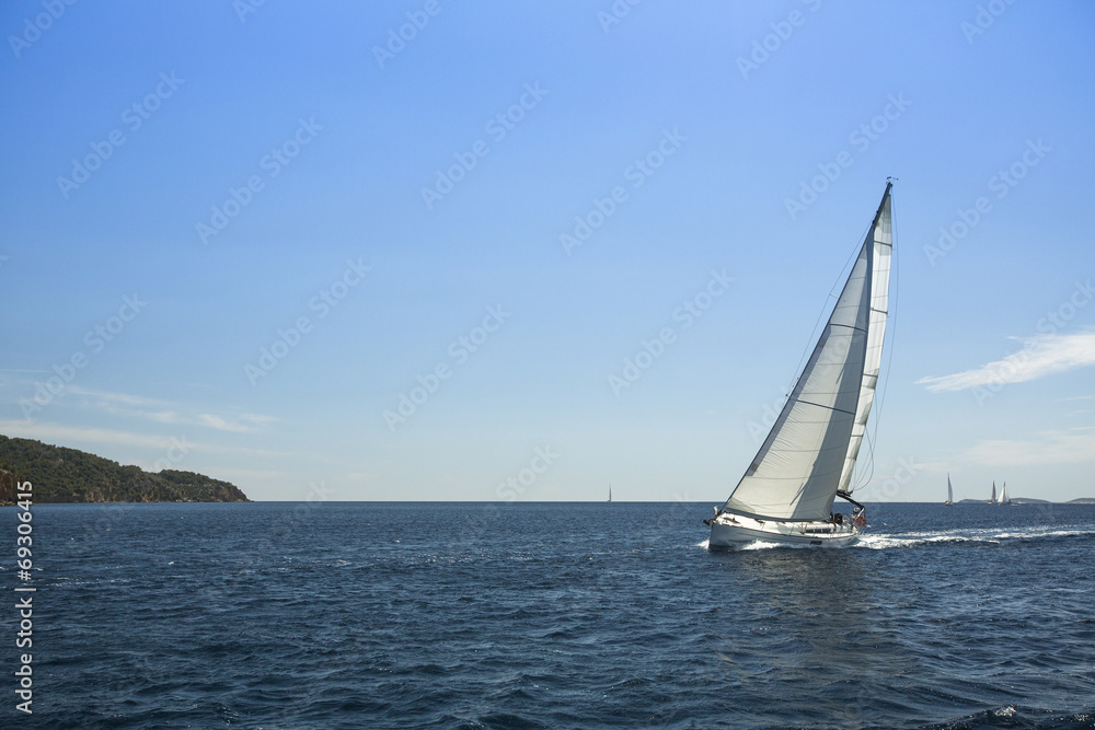 Sailing ship yachts with white sails in the open sea.
