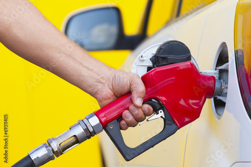 Pumping gas at gas pump. Closeup of man pumping gasoline fuel in
