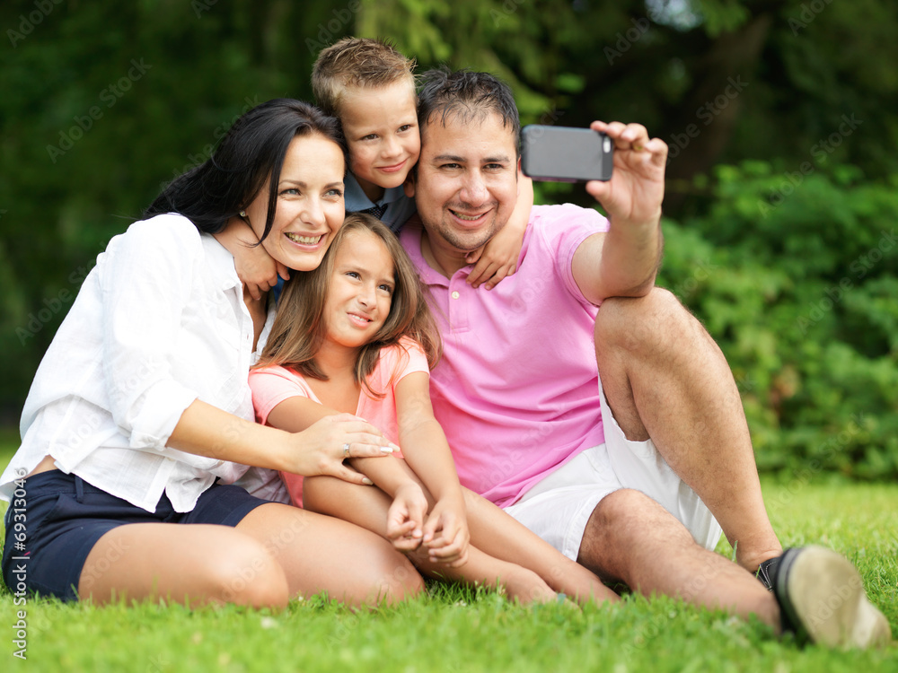 family taking selfies with smartphone in park family taking selfies with smartphone in park