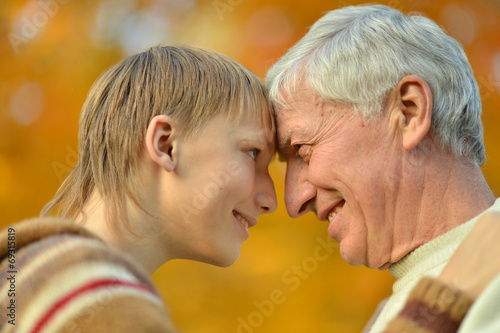 Grandfather with boy in autumn park