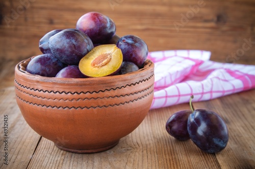 organic ripe plums in a clay bowl