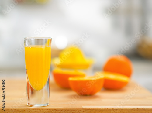 Closeup on glass of fresh orange juice and oranges on table