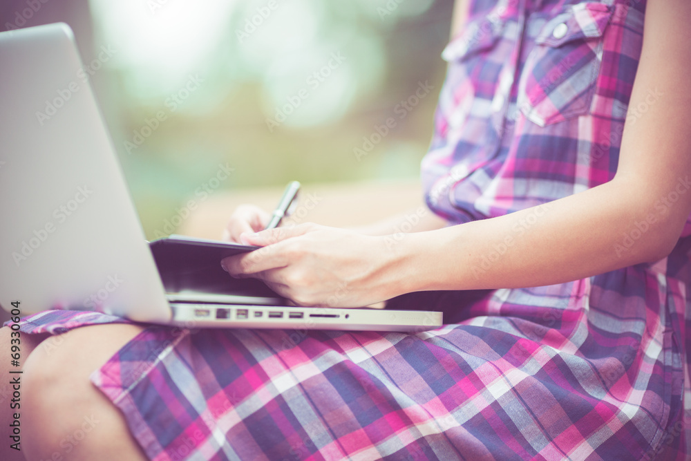 Naklejka premium Beautiful young woman using laptop in park