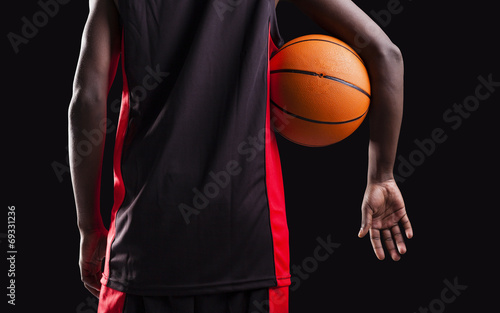Rear view of a basketball player standing with a basket ball on
