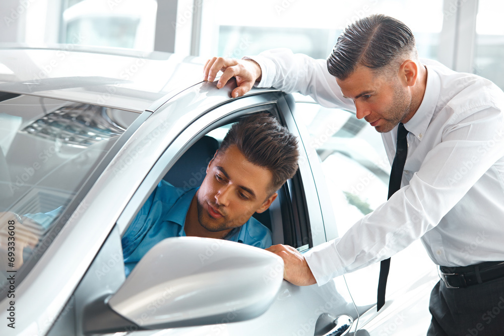 Obraz premium Car Sales Consultant Showing a New Car to a Potential Buyer in S