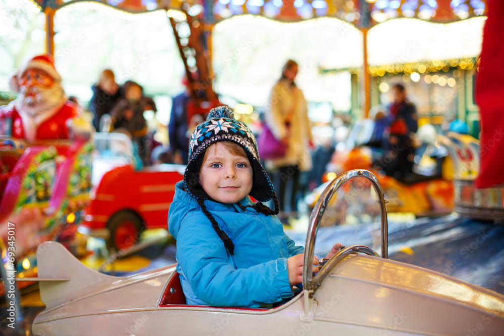 Adorable little boy on a carousel at Christmas funfair or market Adorable little boy on a carousel at Christmas funfair or market