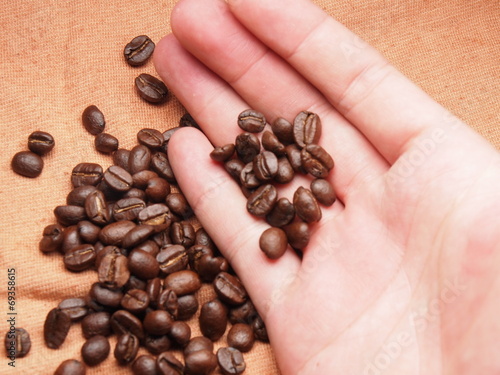 part of hand with coffee crop beans on fabric textile