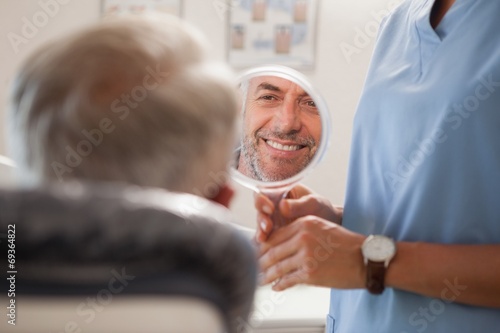 Dentist showing patient his new smile in the mirror