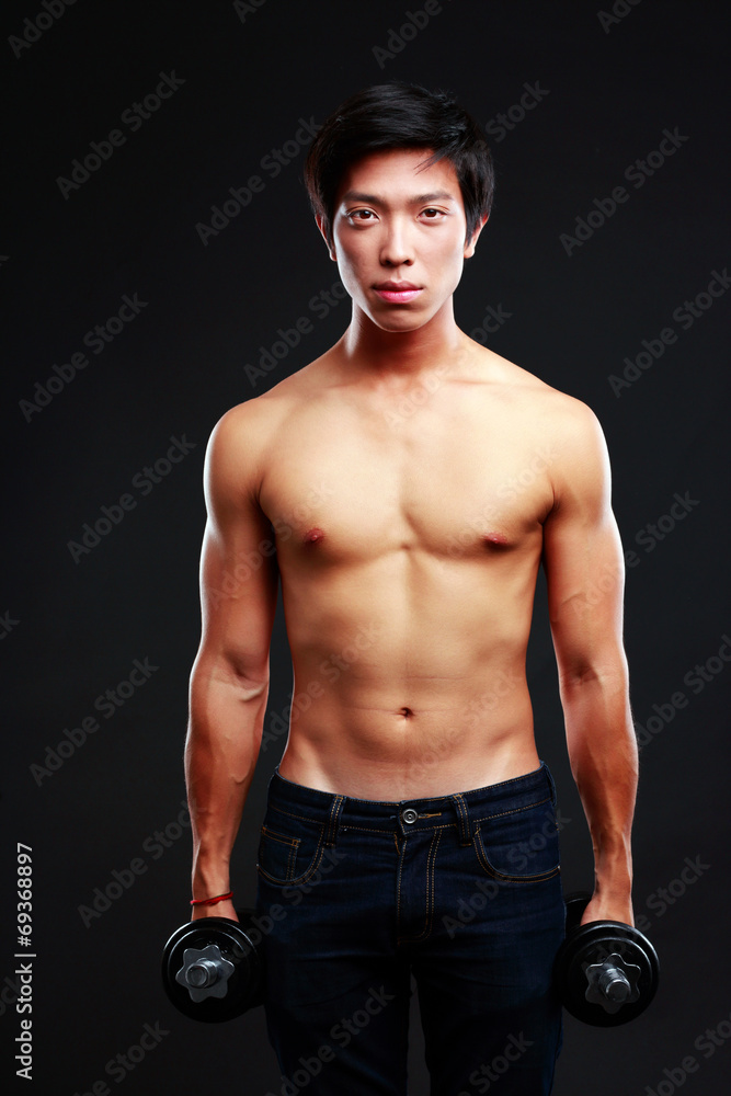 Asian man standing with dumbbells over black background Asian man standing with dumbbells over black background