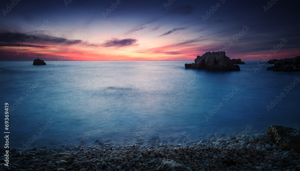 Sea coast under blue sky with clouds at sunset