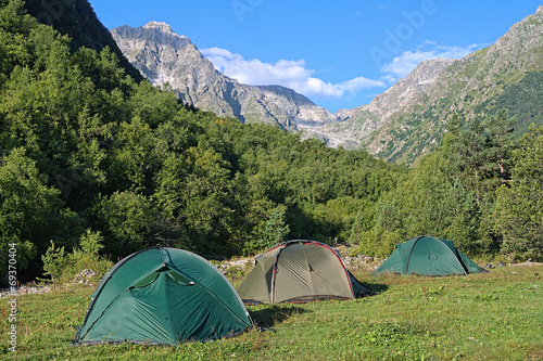 Three camping tents between the mountains