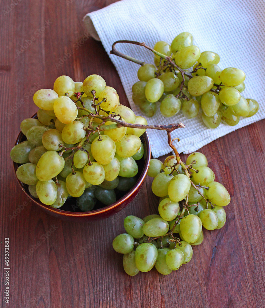 Fresh white grapes in ceramic plate on the wooden table Fresh white grapes in ceramic plate on the wooden table