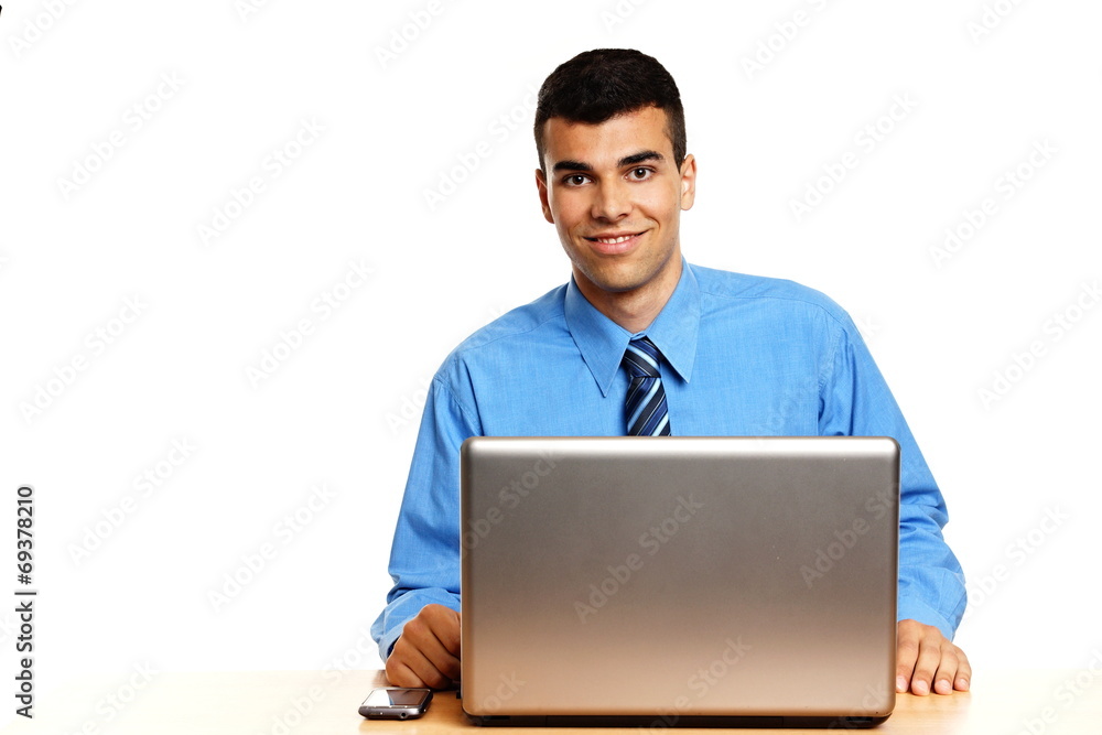 Young businessman in blue shirt sits at the laptop
