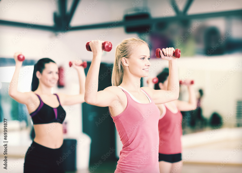 group of smiling women working out with dumbbells group of smiling women working out with dumbbells