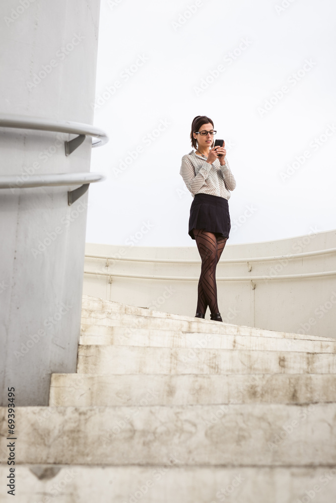 Trendy businesswoman messaging on smartphone