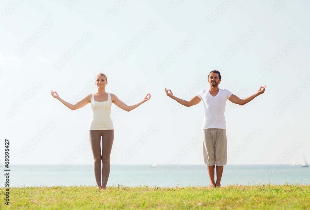 smiling couple making yoga exercises outdoors smiling couple making yoga exercises outdoors