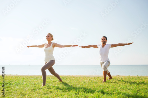 smiling couple making yoga exercises outdoors