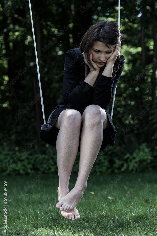 Worried woman sitting on swing