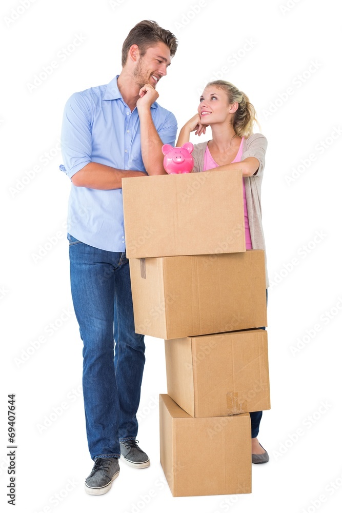 Attractive young couple leaning on boxes with piggy bank Attractive young couple leaning on boxes with piggy bank