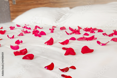 Rose petals on white bedding - romantic bedroom scenery