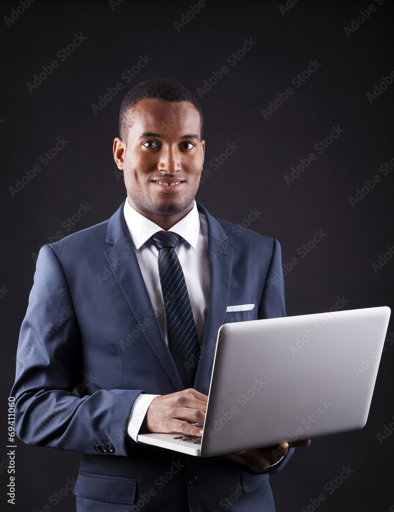 Young business man with a laptop over dark background Young business man with a laptop over dark background