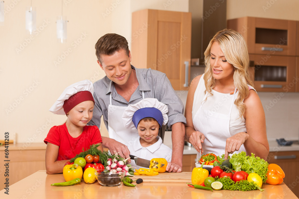 Young father and mother preparing salad together.