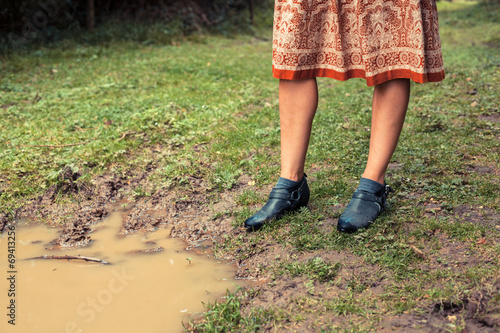 Young woman standing by a puddle in the forest