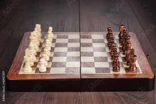 Canvas Print chess board with figures on wooden table