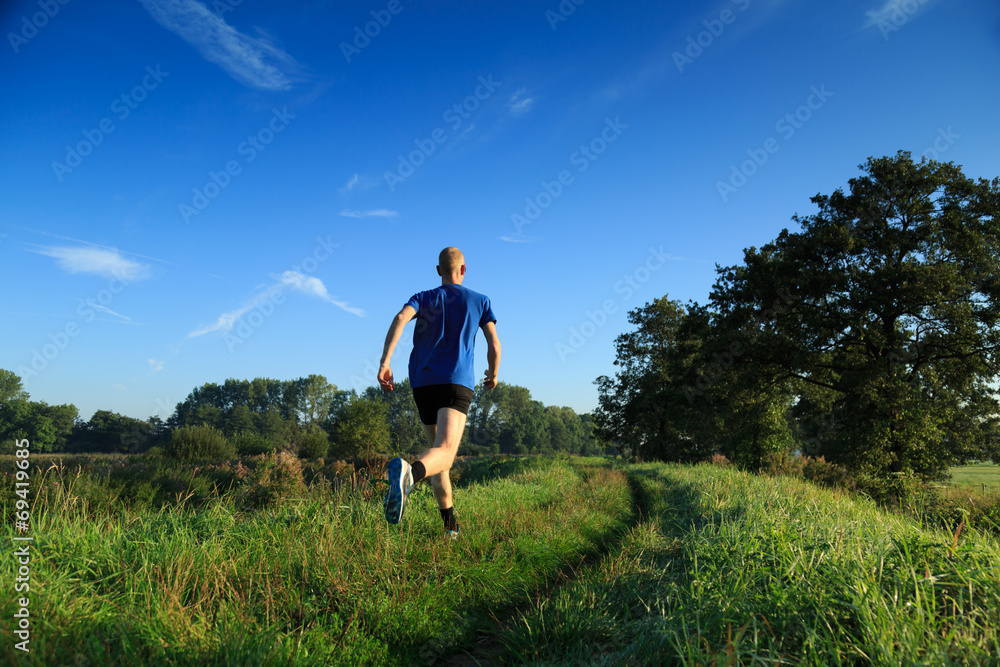 Man trailrunning in the countryside on a sunny morning.