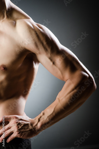 Muscular man posing in dark studio