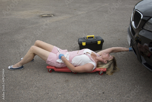 Motor mechanic laying on a crawler to gain access under a car photo