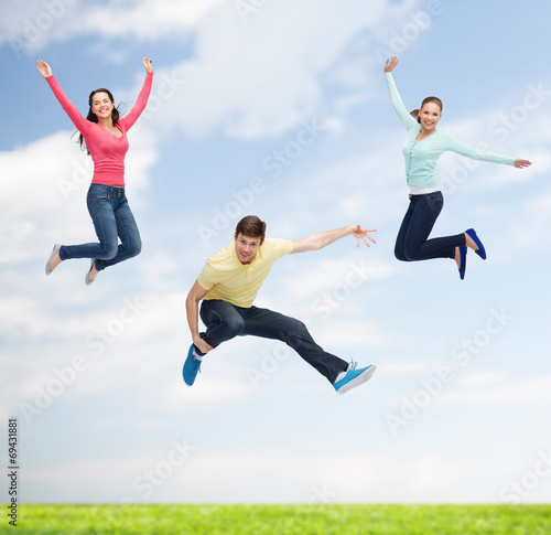 group of smiling teenagers jumping in air