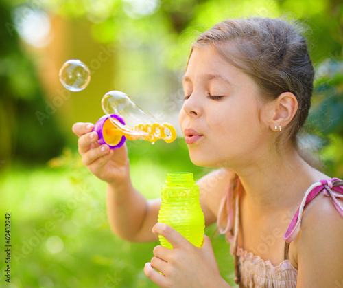 Little girl is blowing a soap bubbles