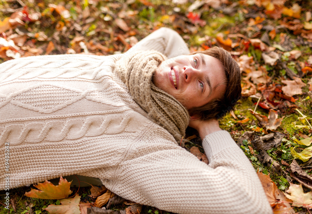 close up of smiling young man lying in autumn park close up of smiling young man lying in autumn park