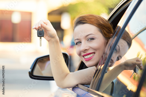 Happy, smiling woman, buyer sitting in her new car showing keys