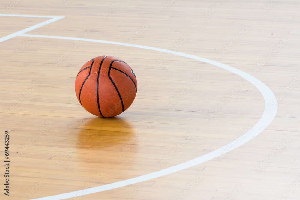 Naklejka premium Basketball ball over floor in the gym