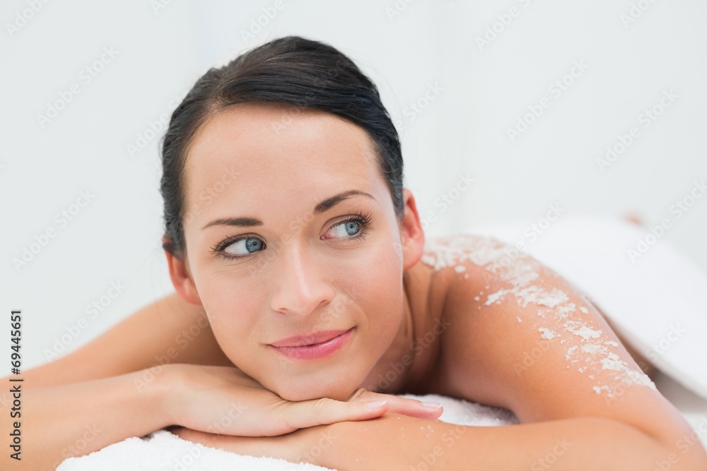 Peaceful brunette lying with salt scrub on back Peaceful brunette lying with salt scrub on back