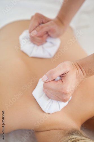 Beautiful blonde enjoying a herbal compress massage