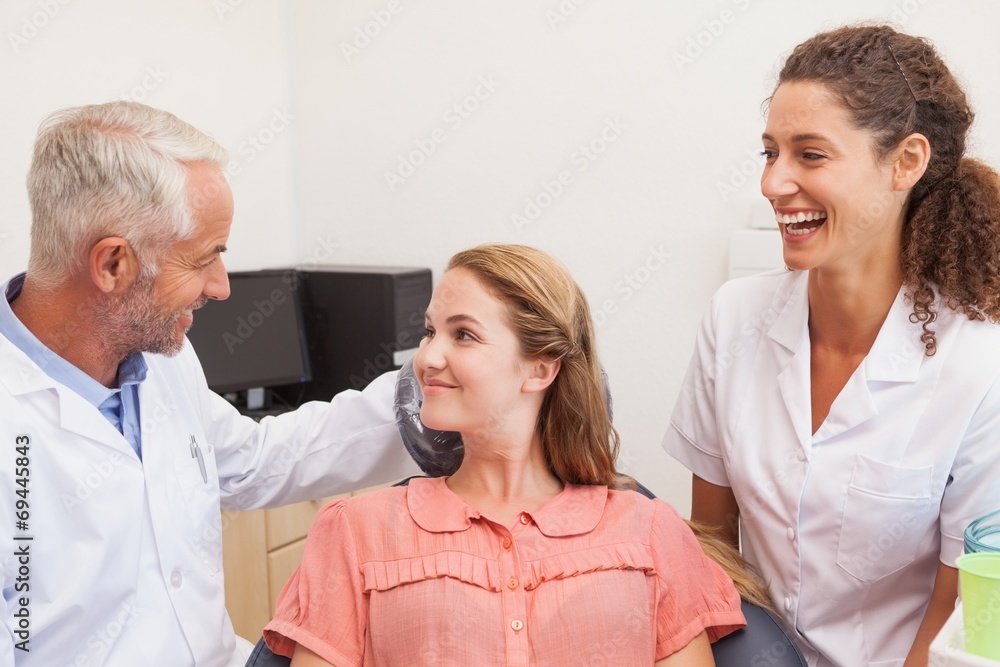 Obraz premium Dentist and assistant smiling with patient in chair